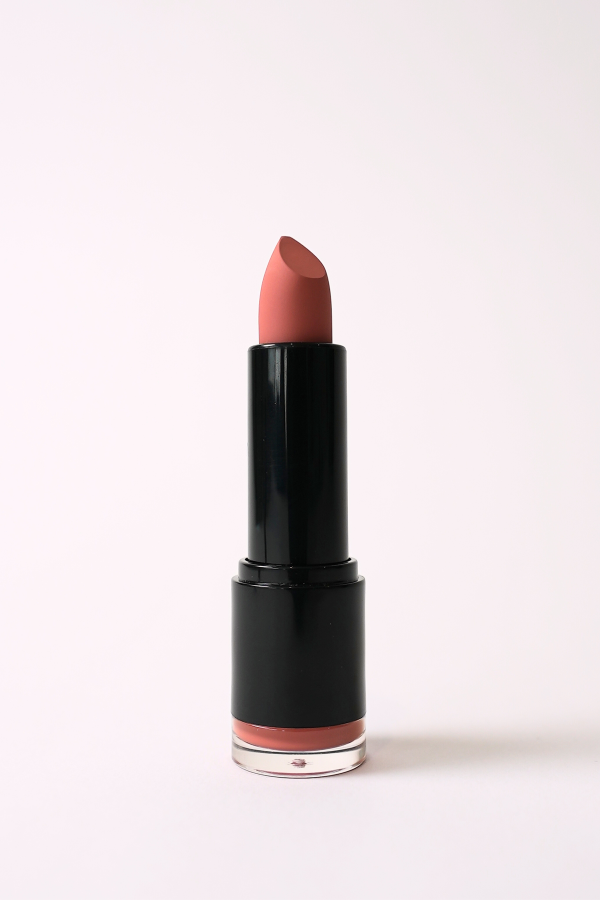‘Bombshell’ soft matte lipstick, a pinky nude shade, standing open in a black tube on a light pink background