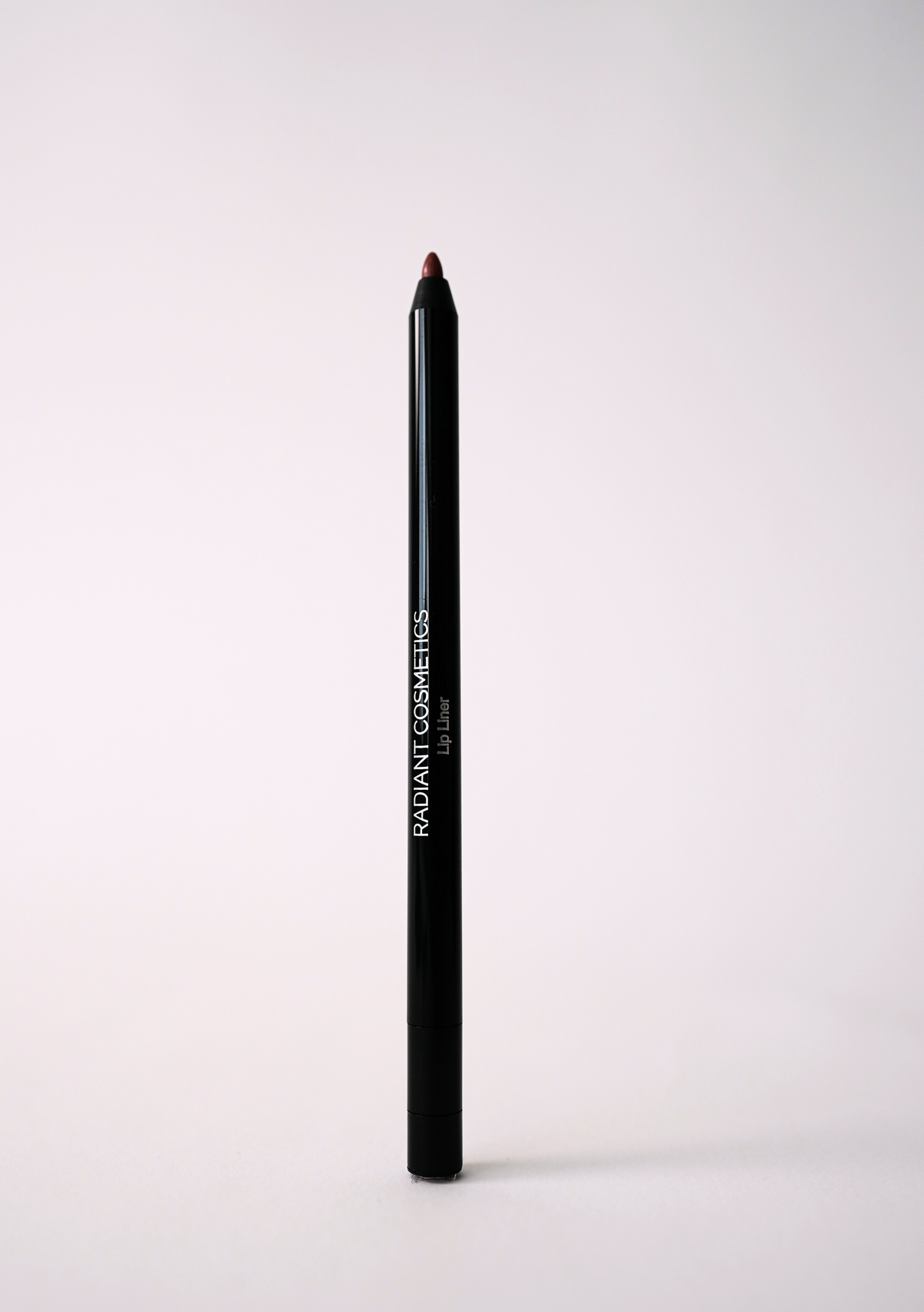 ‘Booked & Busy’ lip liner pencil in a slim black barrel with “Radiant Cosmetics Lip Liner” printed on the side, standing upright on a light background
