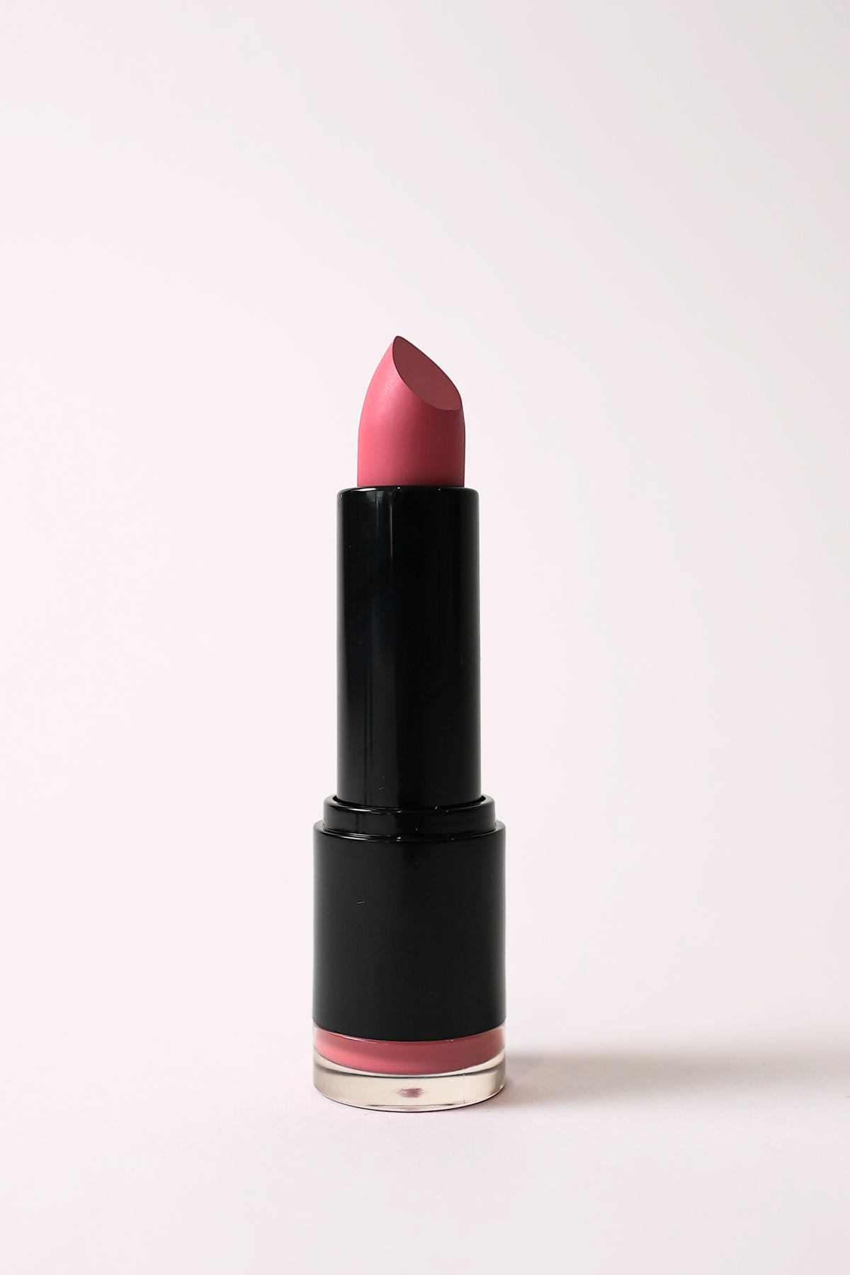 ‘Eye Candy’ soft matte lipstick, a vibrant pink, standing open in a black tube on a light pink background